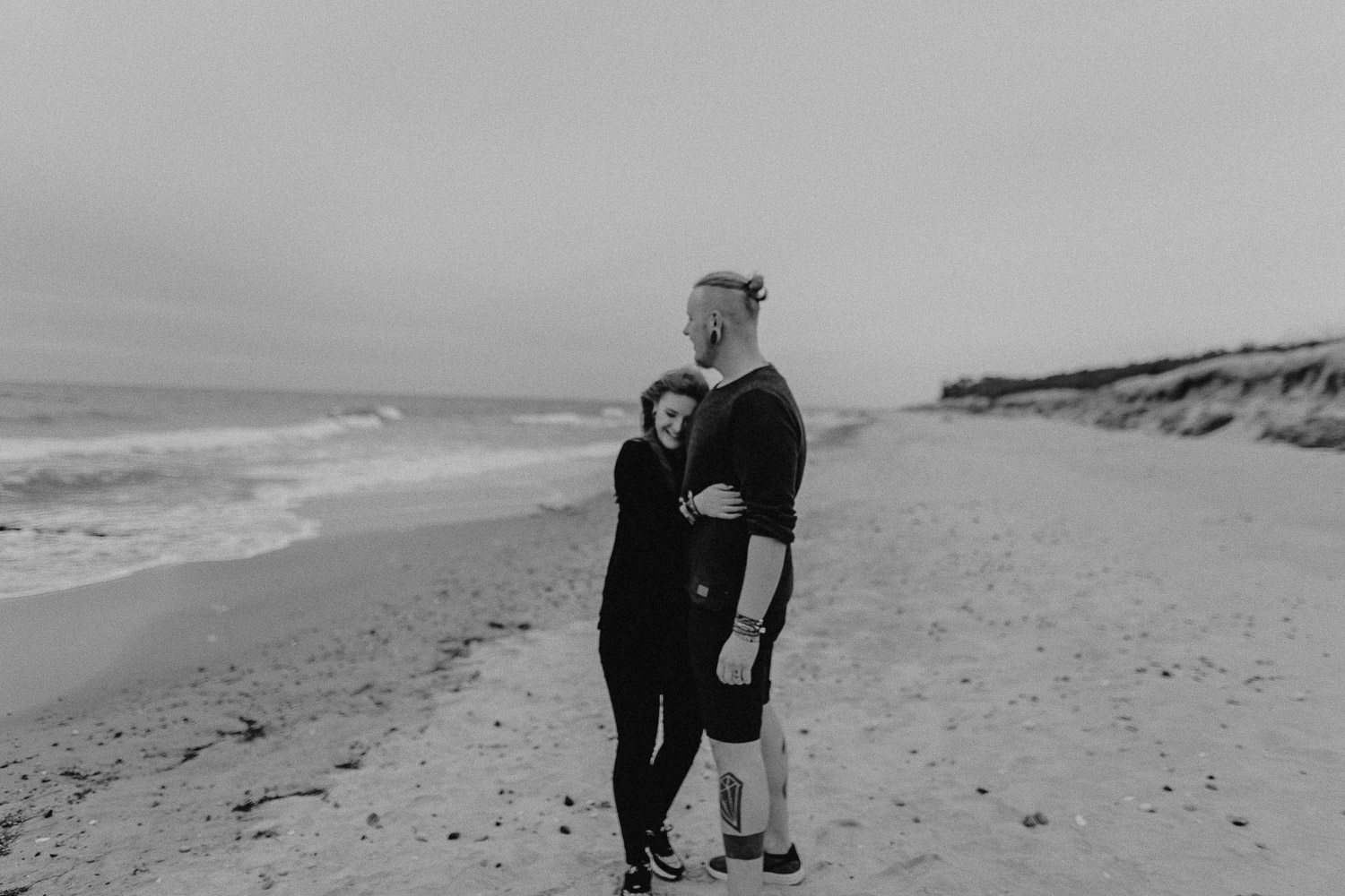 Aufgenommen von Hochzeitsfotograf Kupfergold Photographie aus Rostock. Zu sehen ist ein alternatives tätowiertes Paar am Strand in Torfbrücke